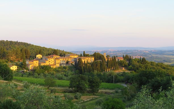 Tuscan village landscape with cypress trees and rolling hills in Chianti Classico region.