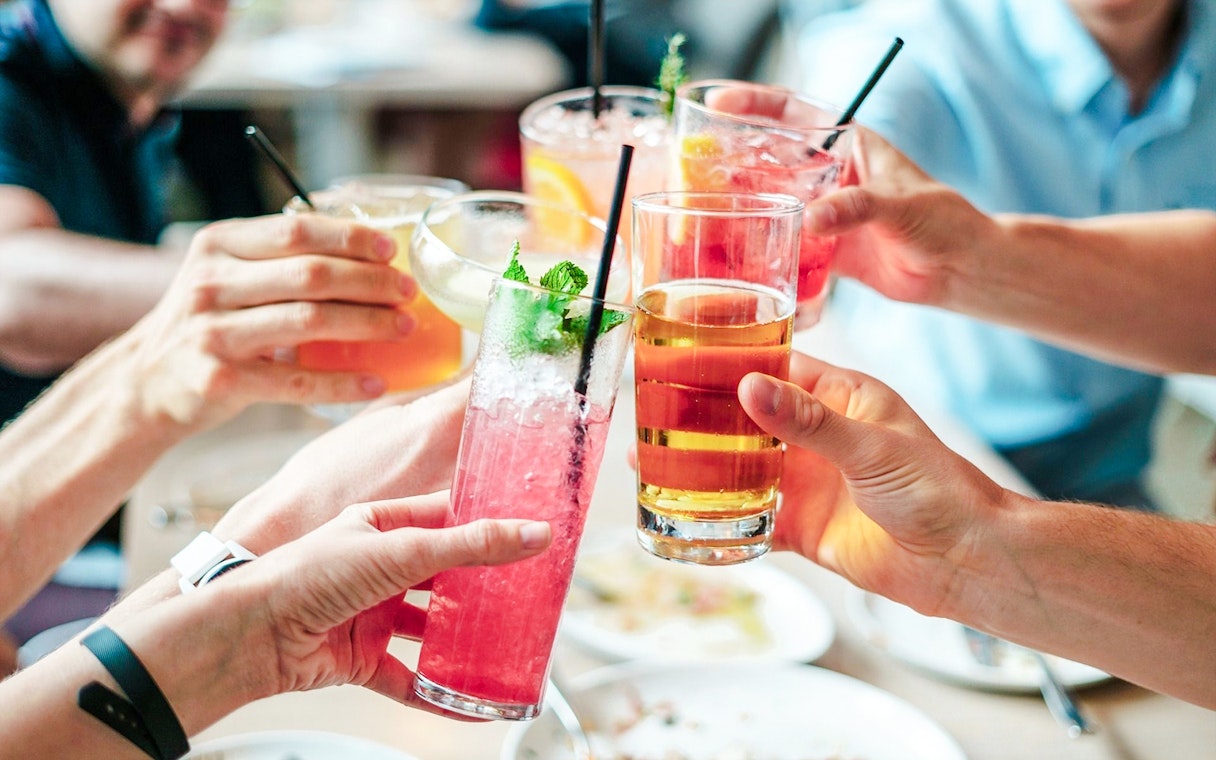 Guests toasting with colorful drinks at a social gathering.