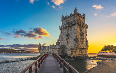 Belem Tower in Lisbon with a sunset sky and river view.