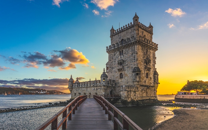 Belem Tower in Lisbon with a sunset sky and river view.