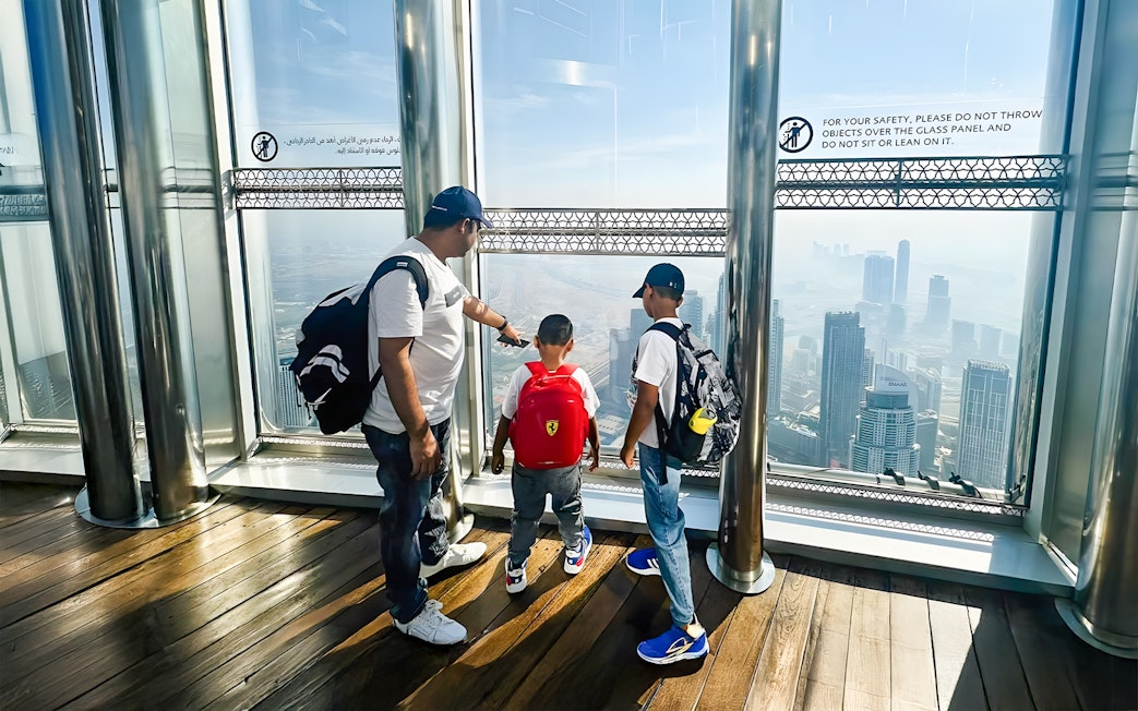 Family enjoying the view from The View At The Palm, overlooking Dubai skyline.