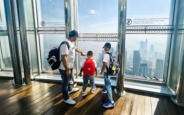 Family enjoying the view from The View At The Palm, overlooking Dubai skyline.