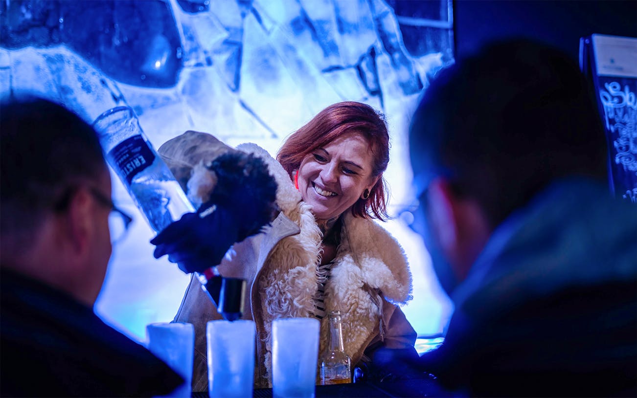 Bartender pouring drinks at Berlin Icebar with ice sculptures in the background.