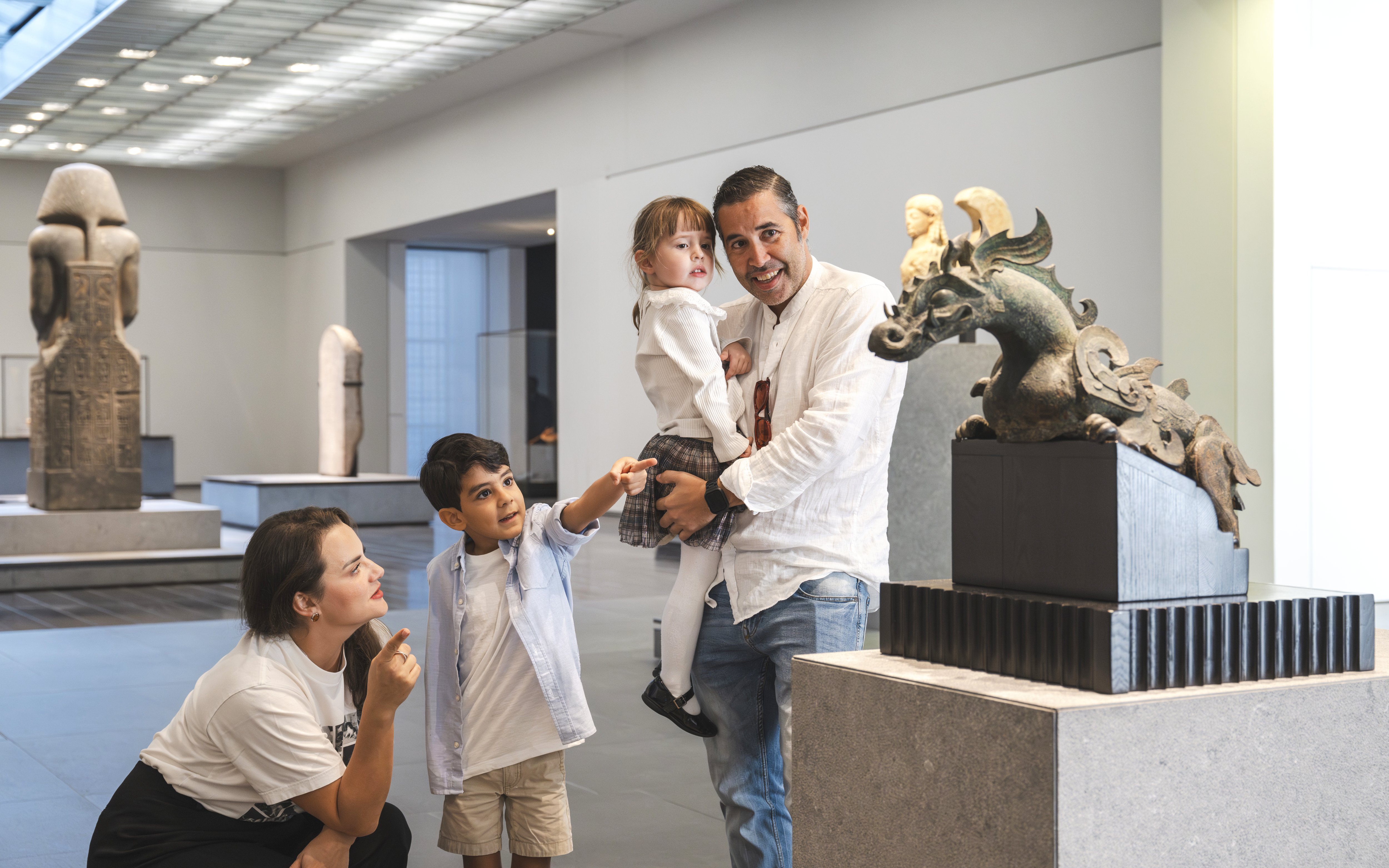 Family exploring sculptures at Louvre Abu Dhabi gallery.