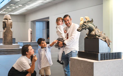 Family exploring sculptures at Louvre Abu Dhabi gallery.