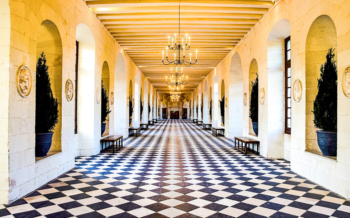 Grand hallway with checkered floor and chandeliers at Château de Chenonceau, France.