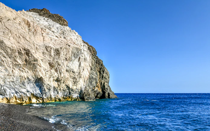 Cliffs and blue sea on a Santorini luxury catamaran cruise route.