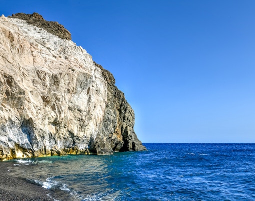 Cliffs and blue sea on a Santorini luxury catamaran cruise route.