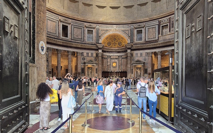 Tourists exploring the interior of the Rome Pantheon, an ancient Roman temple.