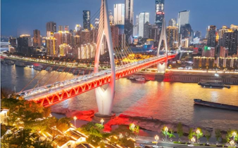 Chongqing skyline with illuminated bridge over Yangtze River at night.