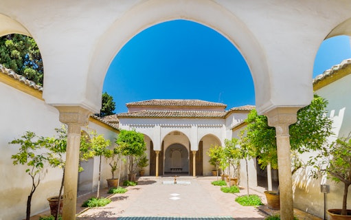 Alcazaba courtyard with arches and potted trees in Malaga, Spain.