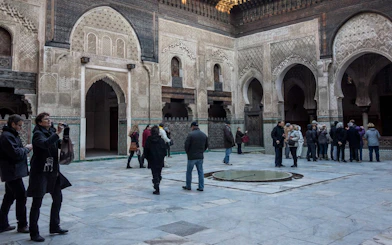 Visitors exploring the courtyard of Attarine Madrasa in Fes Medina.