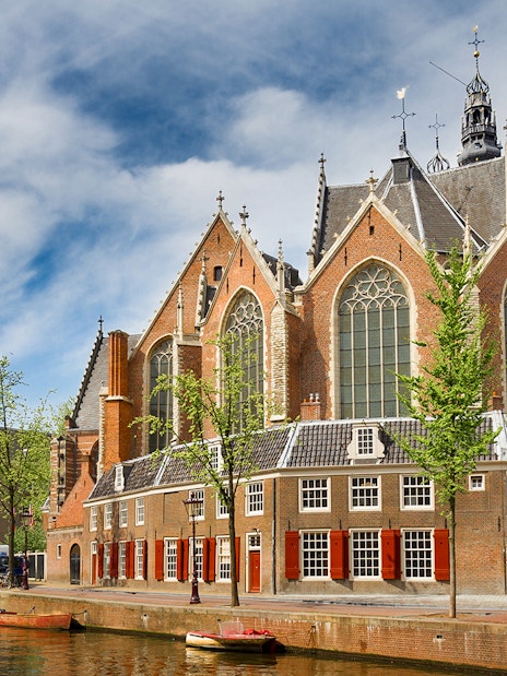 Oude Kerk in Amsterdam with canal and bridge in foreground.