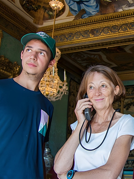 Visitors using audio guides inside Vaux-le-Vicomte, Paris tour.