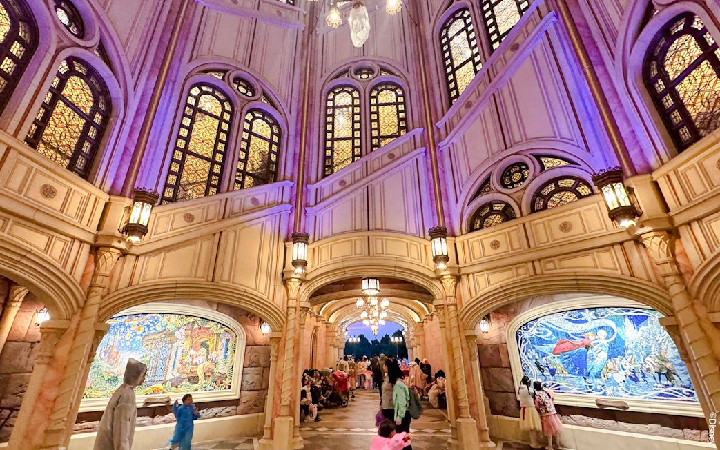 Interior of Shanghai Disney castle with stained glass windows and mosaic murals.