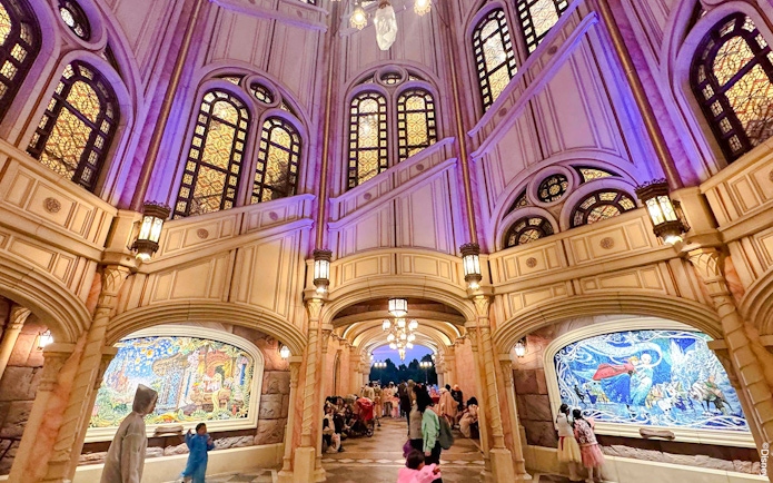 Interior of Shanghai Disney castle with stained glass windows and mosaic murals.