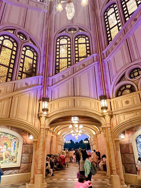 Interior of Shanghai Disney castle with stained glass windows and mosaic murals.
