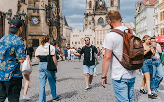 Tour group exploring Prague's Old Town Square with Astronomical Clock in view.