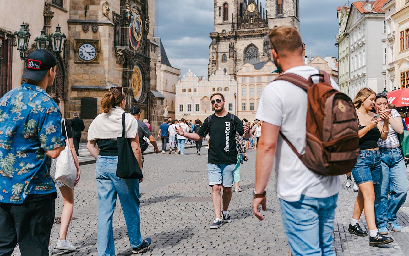 Tour group exploring Prague's Old Town Square with Astronomical Clock in view.