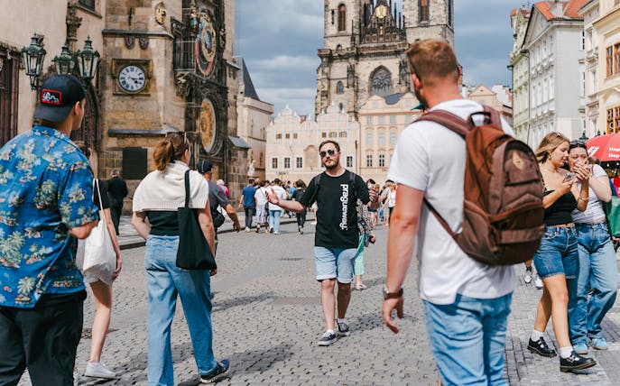 Tour group exploring Prague's Old Town Square with Astronomical Clock in view.