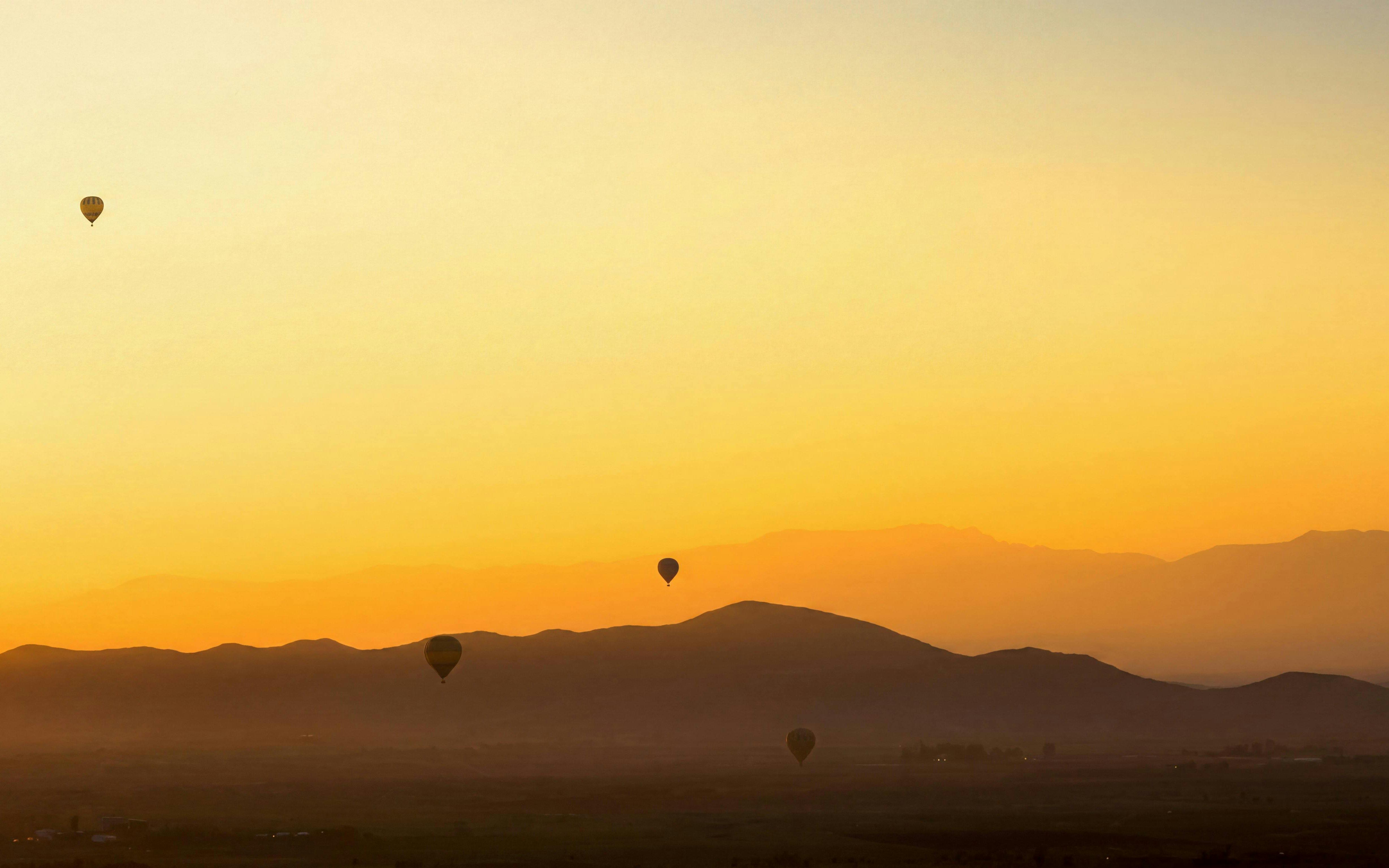 Hot air balloons over Marrakech landscape at sunrise.