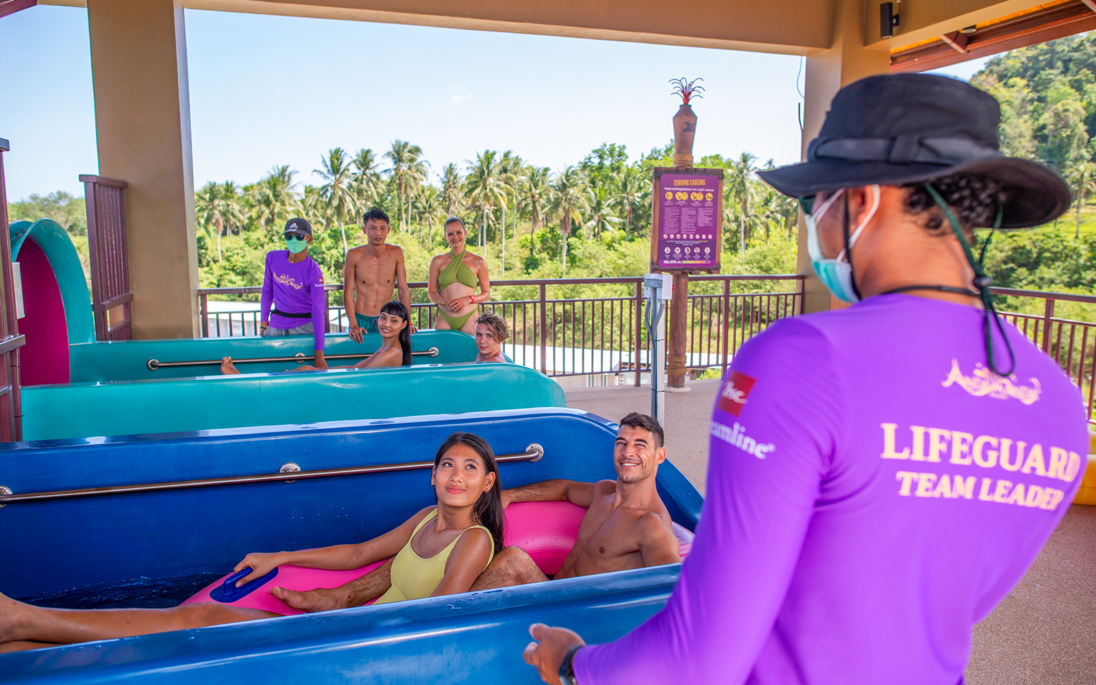 People in swimwear on water ride at Curving Caverns, Andamanda Phuket, with lifeguard nearby.