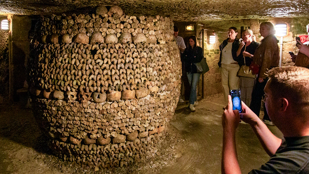 Tourists with guide exploring Paris Catacombs, unique underground tour in France.