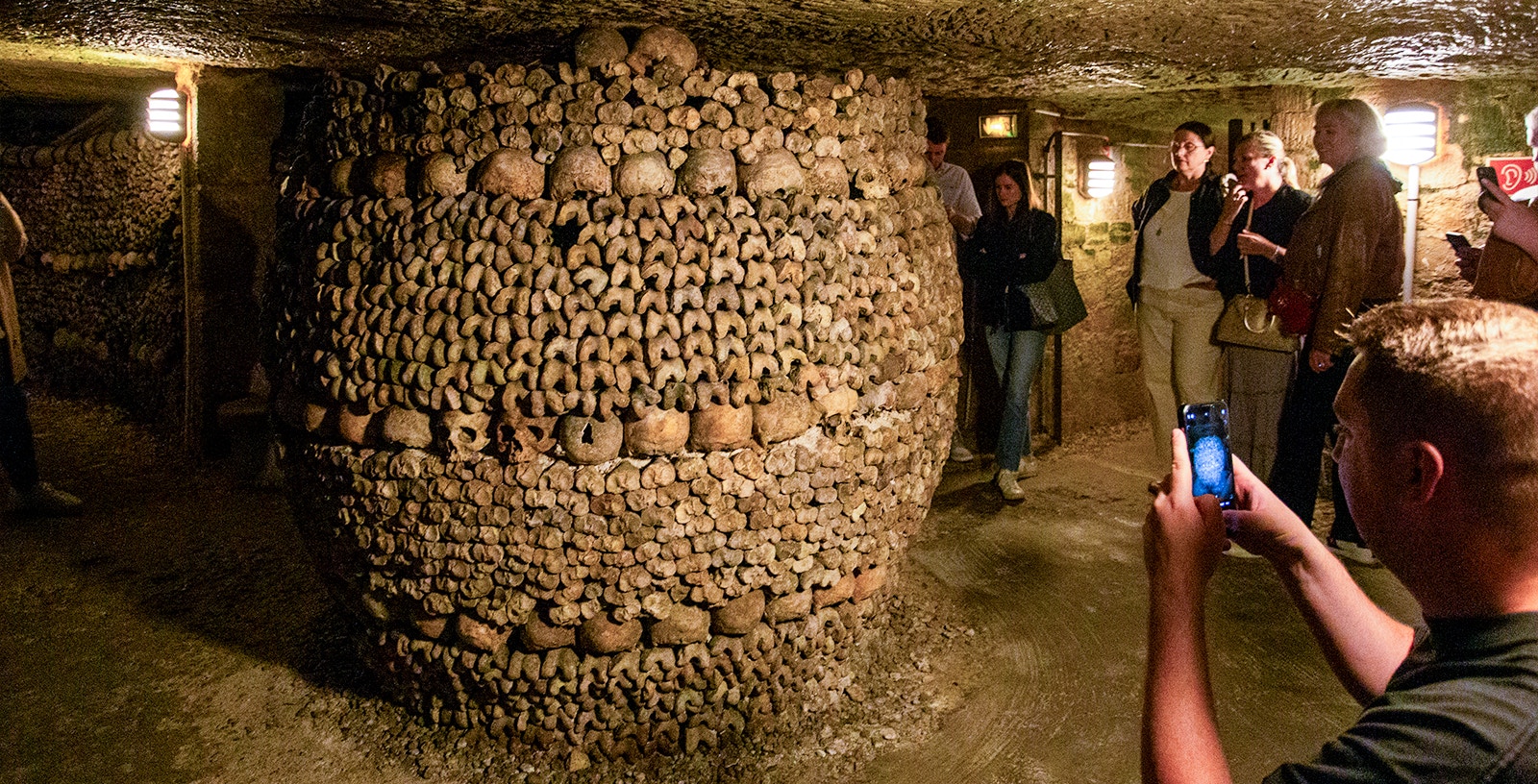 Tourists with guide exploring Paris Catacombs, unique underground tour in France.