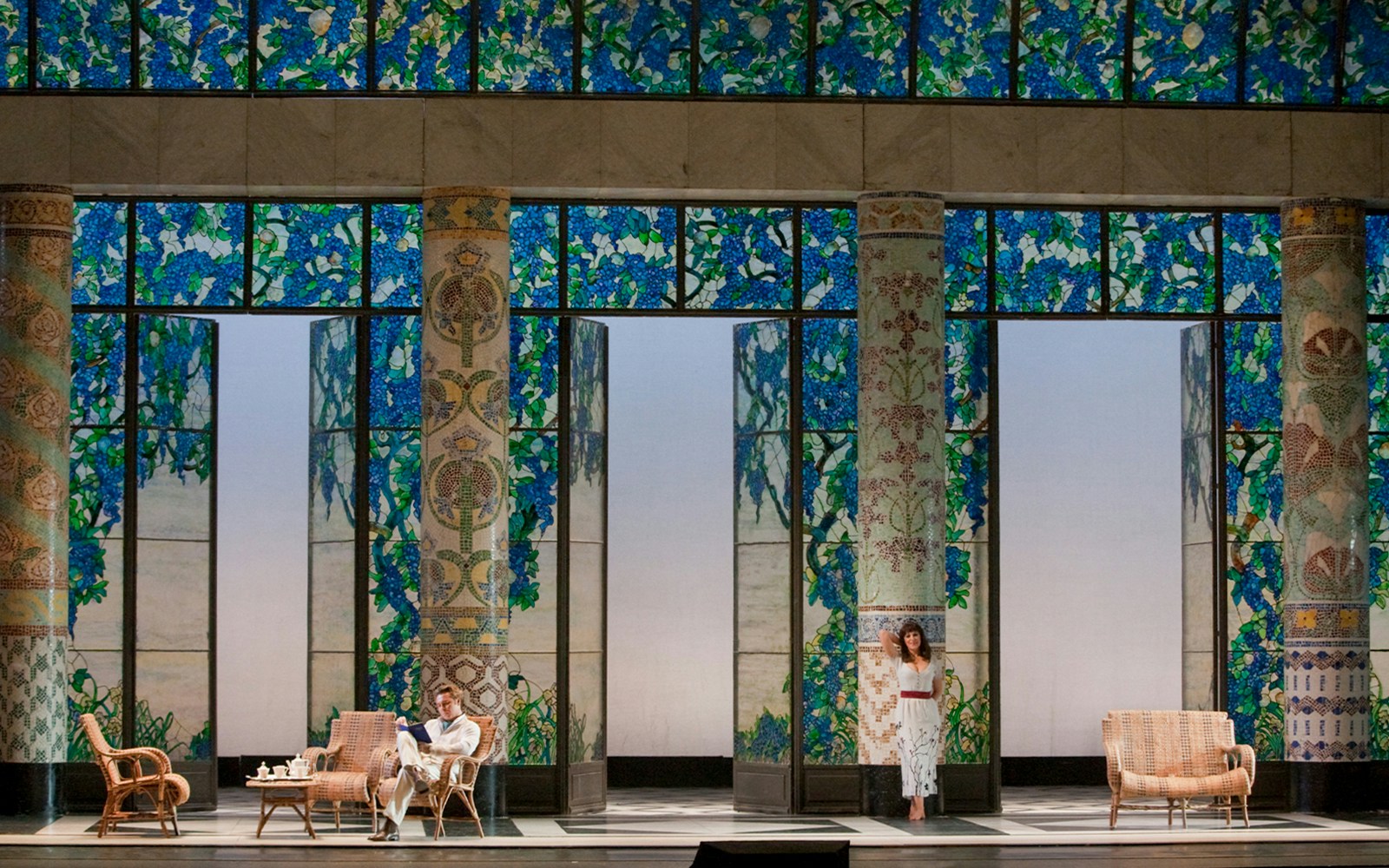 Opera scene from La Rondine with actors on a stage featuring stained glass and ornate columns.