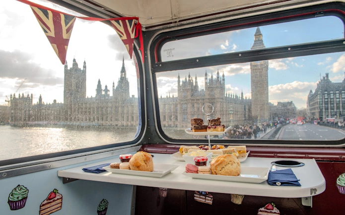 Afternoon tea setup on a bus with a view of Big Ben and the Houses of Parliament in London.