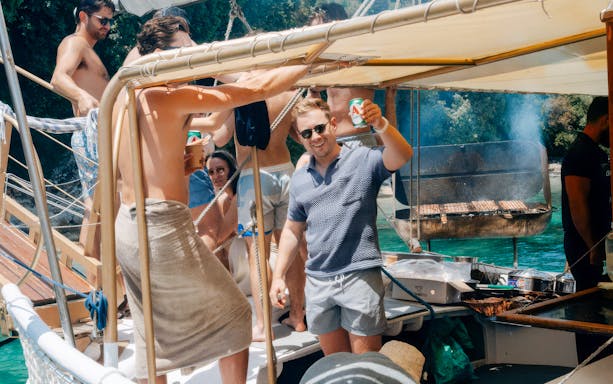 People enjoying a barbecue on a boat during a full-day cruise in Corfu.