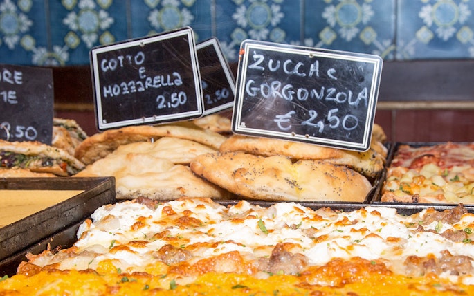 Italian focaccia and pizza with mozzarella and gorgonzola on display in a bakery.