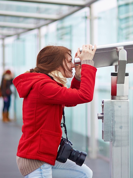 Visitor using telescope on Montparnasse Tower 56th Floor terrace, Paris.