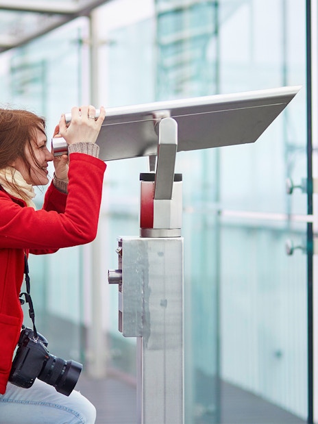 Visitor using telescope on Montparnasse Tower 56th Floor terrace, Paris.