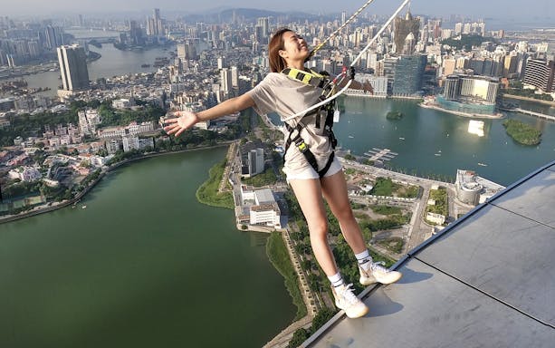 Person bungee jumping at Skypark Macau by AJ Hackett with cityscape view.