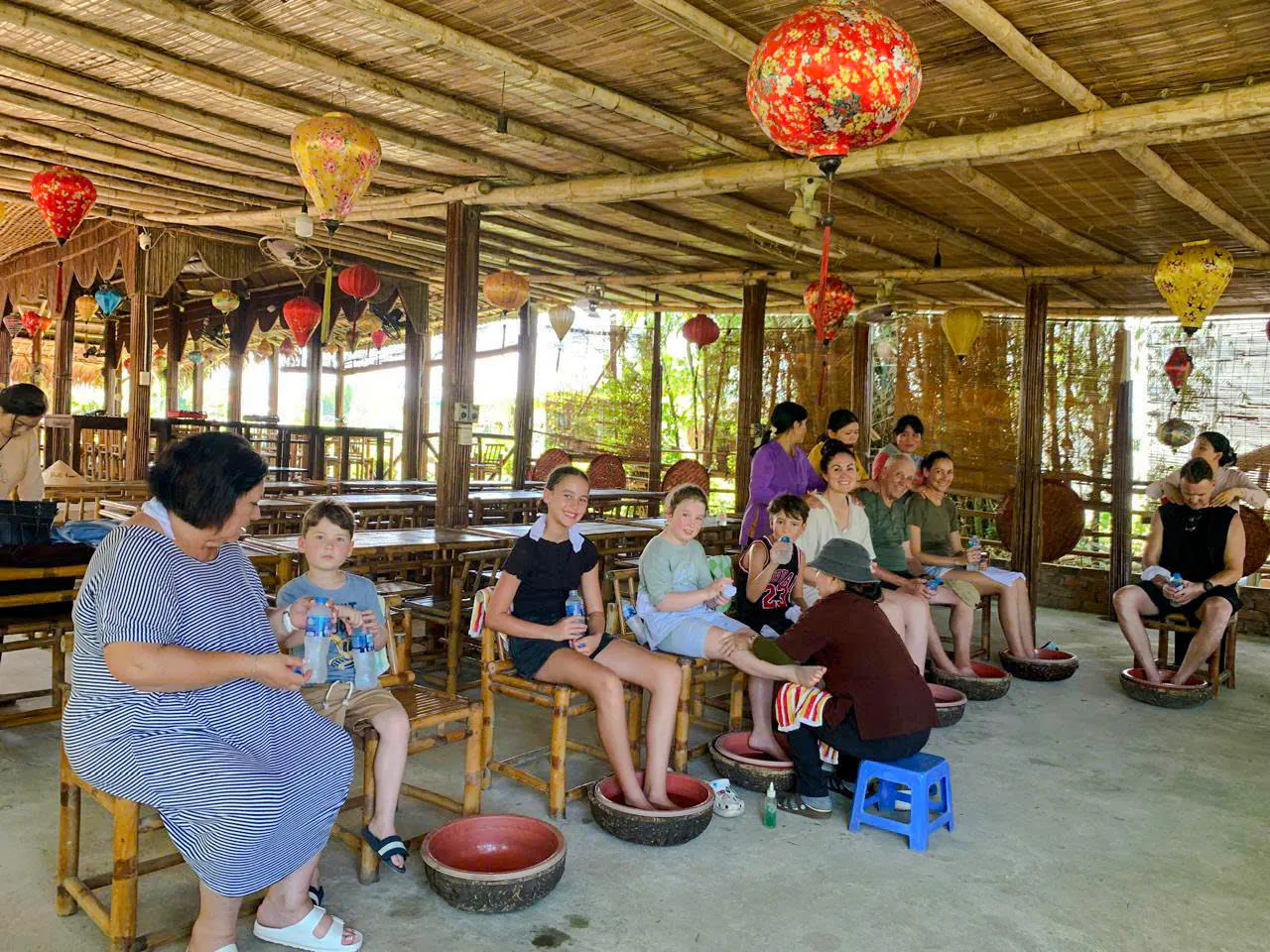 Visitors enjoying foot baths and massages at a craft village on the Hoi An bicycle tour.