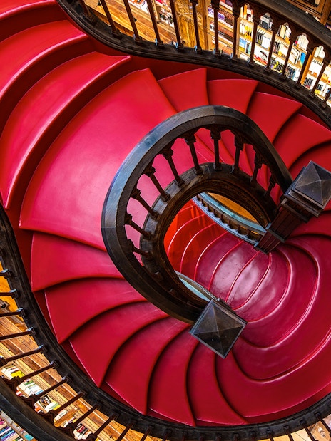 Spiral staircase at Lello Library in Porto, Portugal, surrounded by bookshelves.