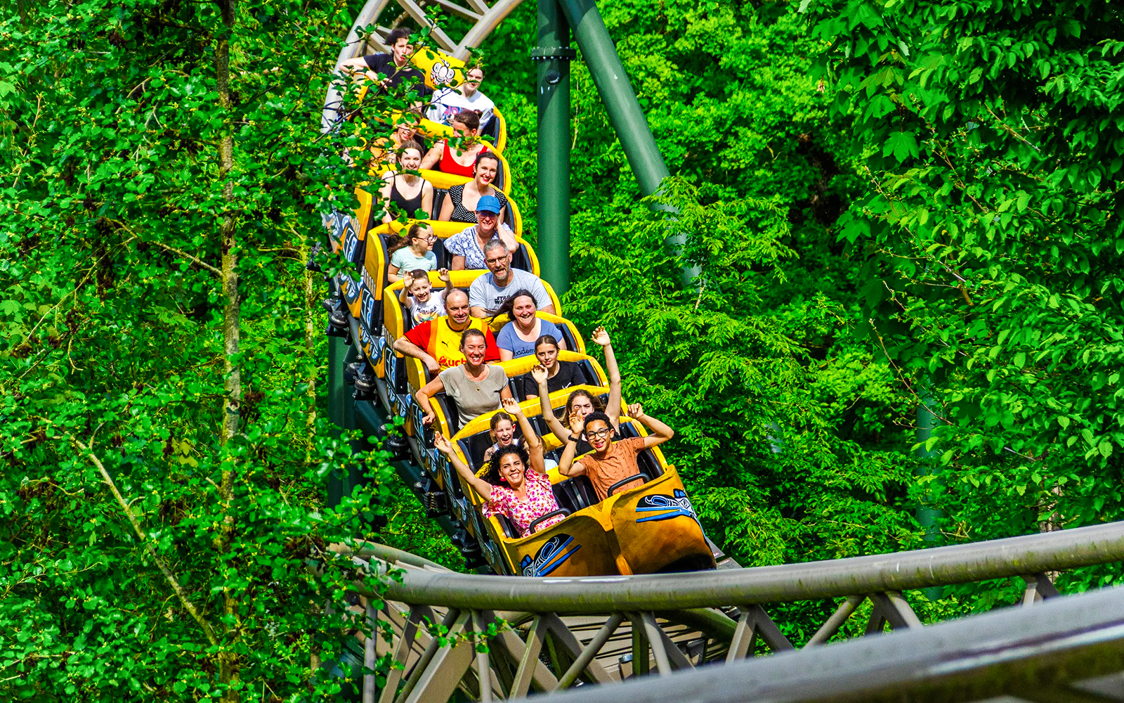 People enjoying a ride on a boomerang roller coaster surrounded by lush greenery.
