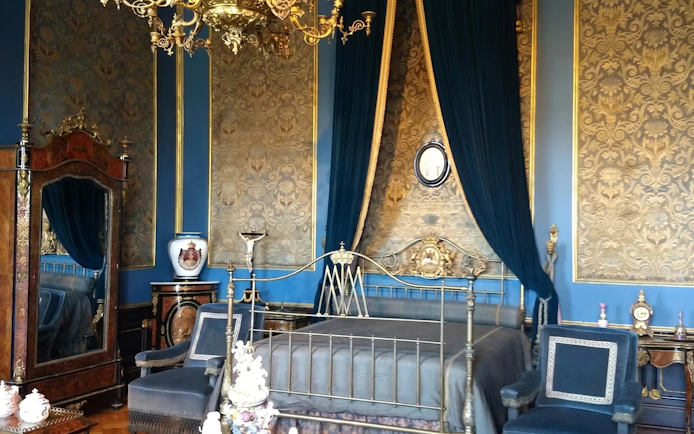 Chapultepec Castle bedroom with ornate bed, antique furniture, and decorative wallpaper.
