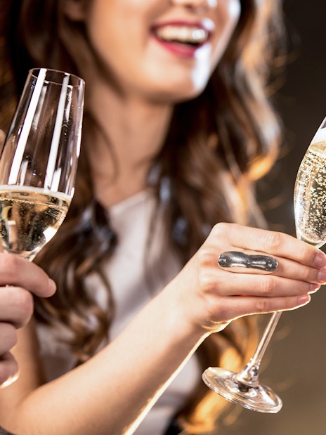 Barista pouring Champagne into a glass at a social gathering.