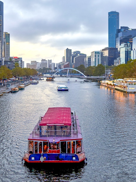 Dinner cruise boat on Yarra River with Melbourne skyline in the background.