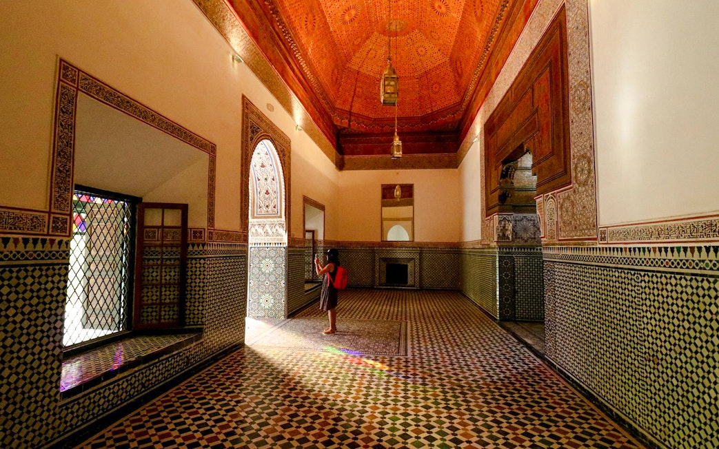 Girl photographing intricate tilework in Bahia Palace hallway, Marrakech.