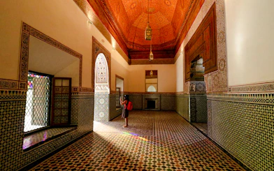 Girl photographing intricate tilework in Bahia Palace hallway, Marrakech.