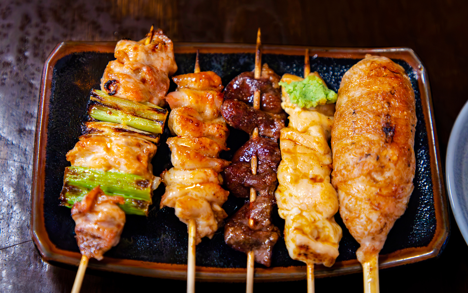 Assorted yakitori skewers on a plate, featuring grilled chicken and vegetables.