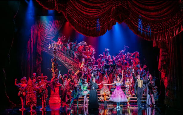 Phantom of the Opera cast performing a vibrant masquerade ball scene on stage.
