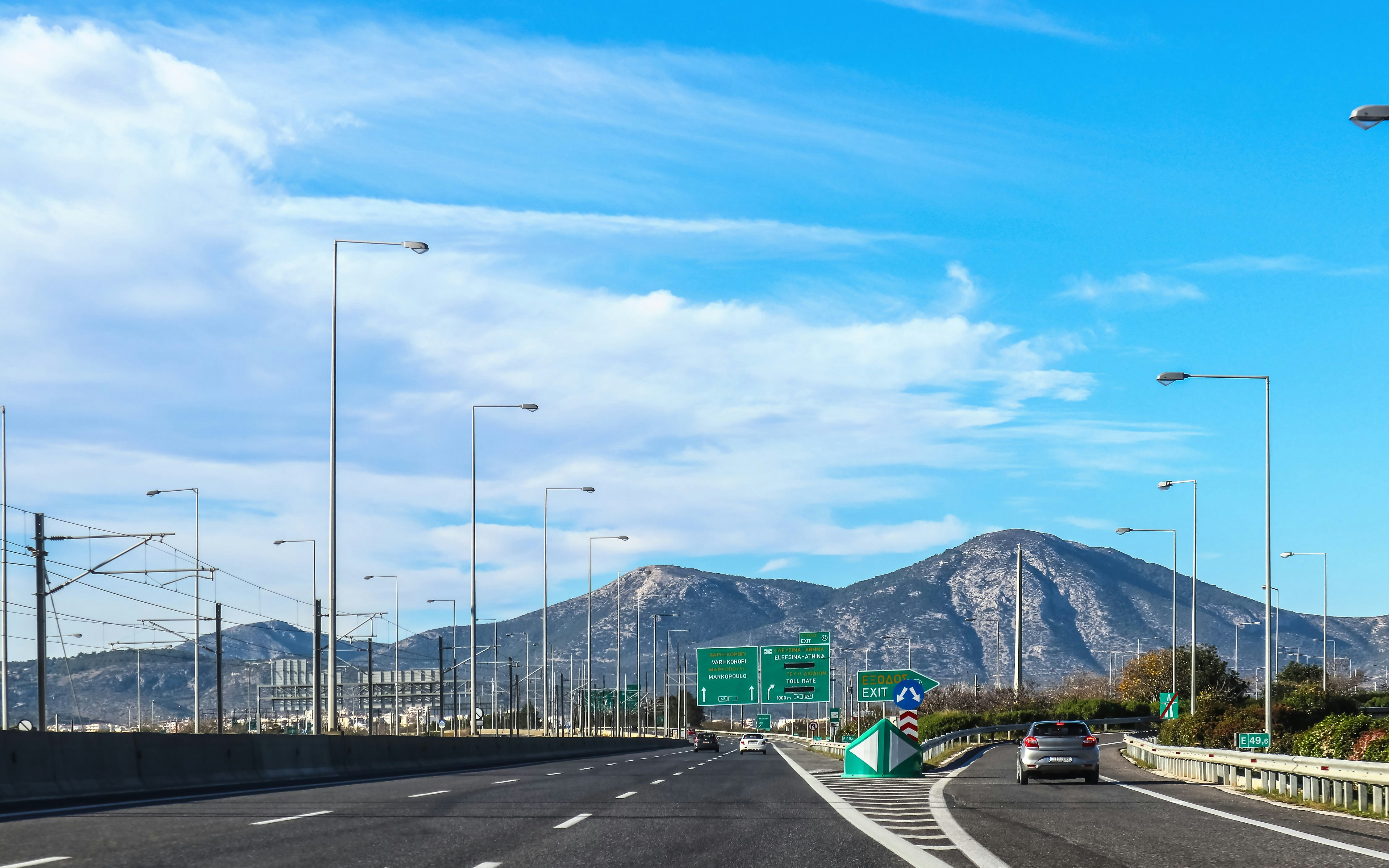 Highway exit in Greece leaving Athens toward Peloponnese Peninsula with mountains in background.