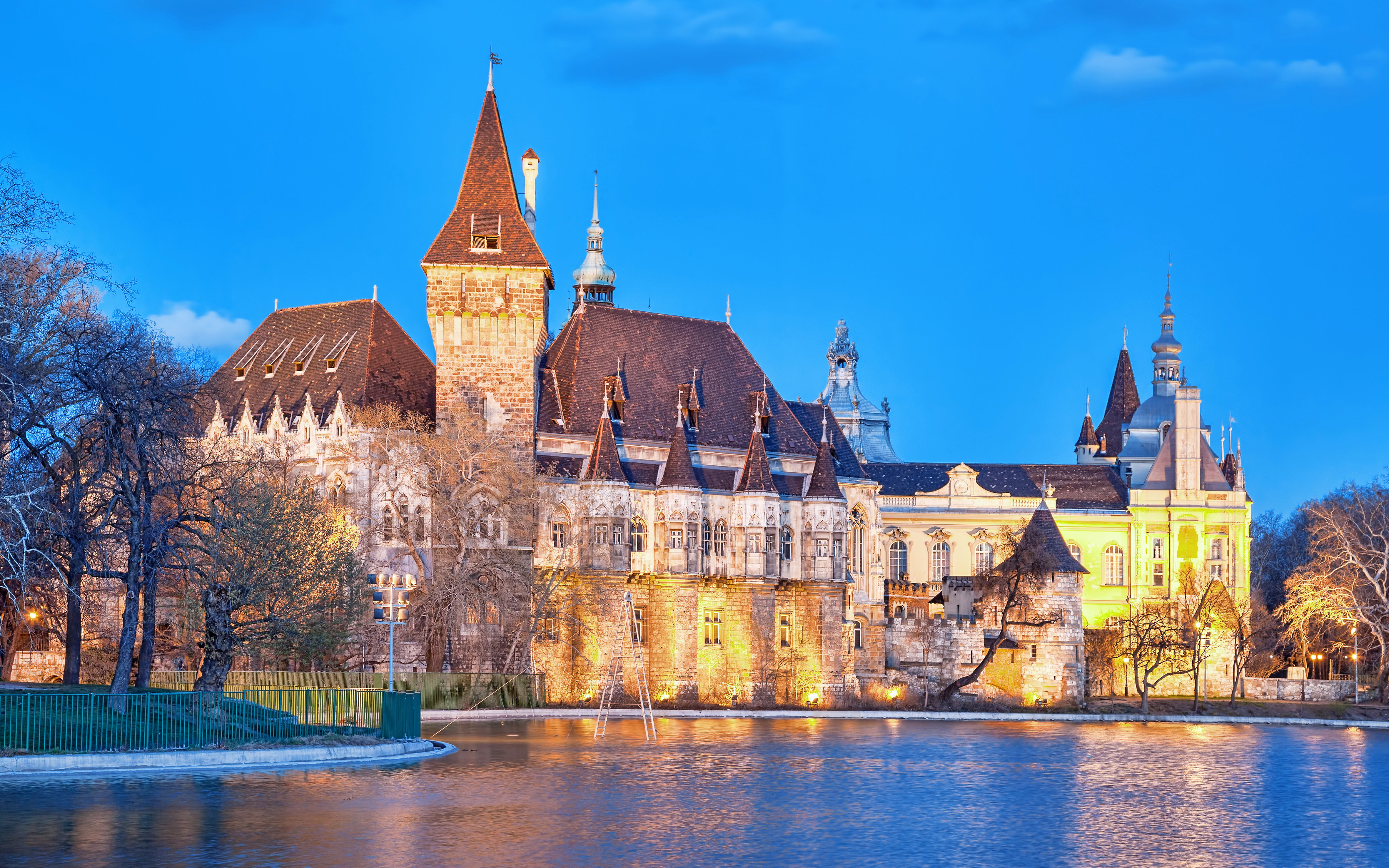 Vajdahunyad Castle illuminated by evening lights with lake reflection, Budapest, Hungary.