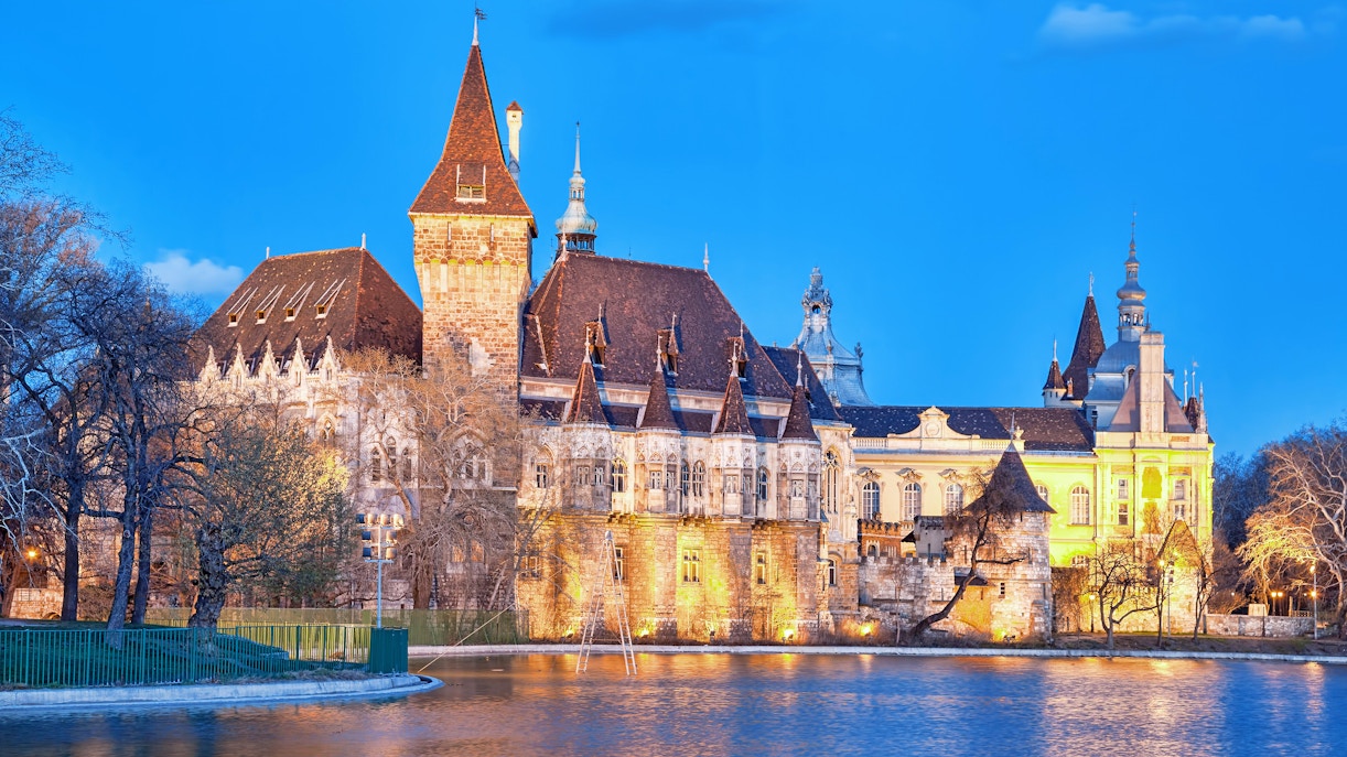 Vajdahunyad Castle illuminated by evening lights with lake reflection, Budapest, Hungary.