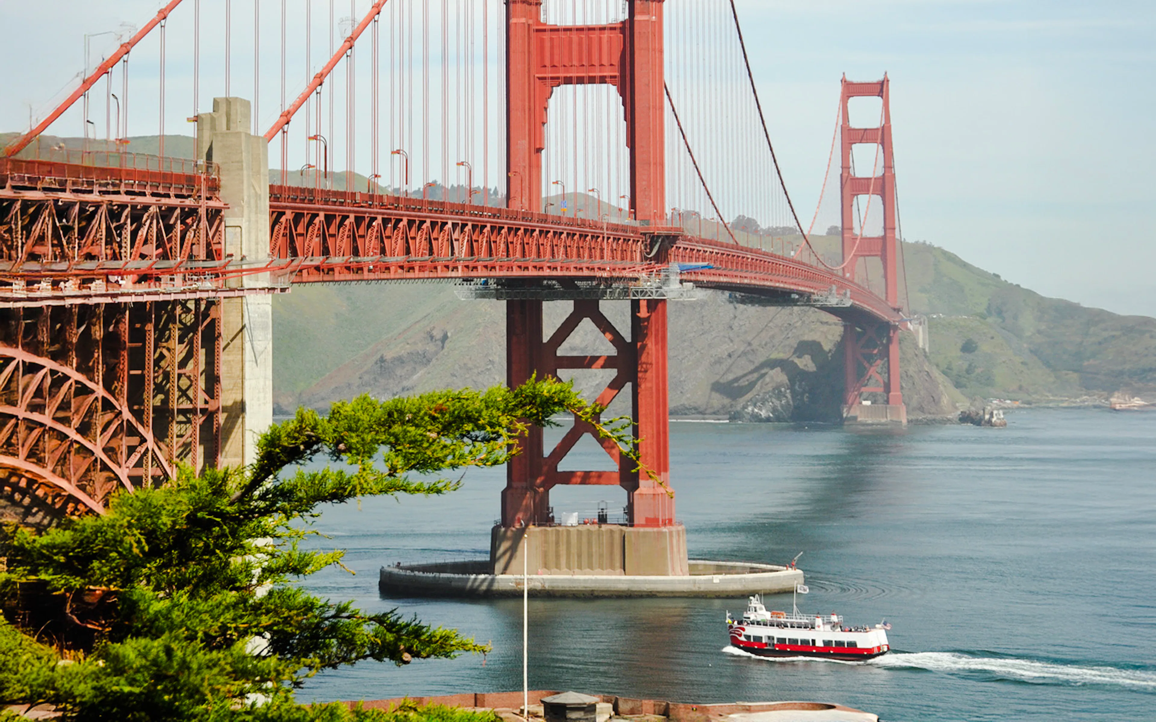 Golden Gate Bridge with a cruise boat passing underneath in San Francisco Bay.