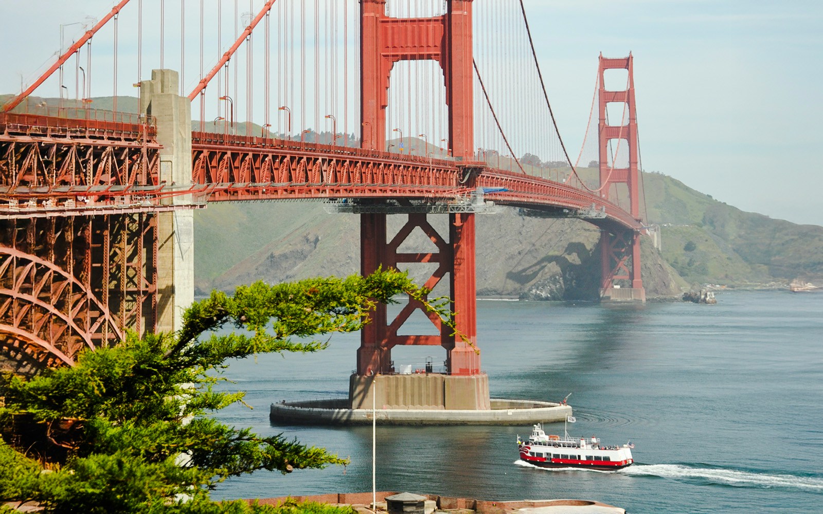 Golden Gate Bridge with a cruise boat passing underneath in San Francisco Bay.